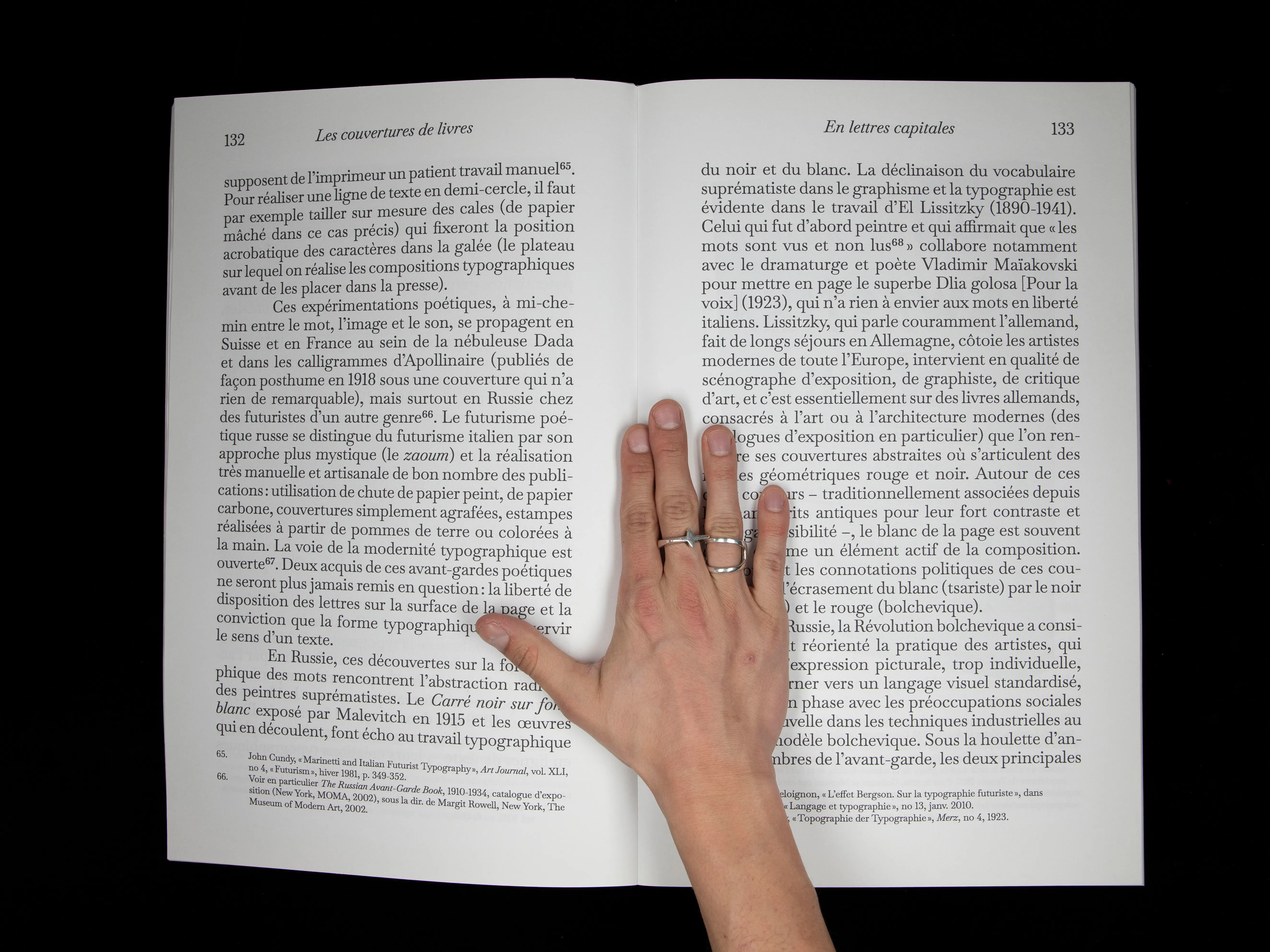Double page de texte du chapitre En lettres capitales, maintenue ouverte à la main.